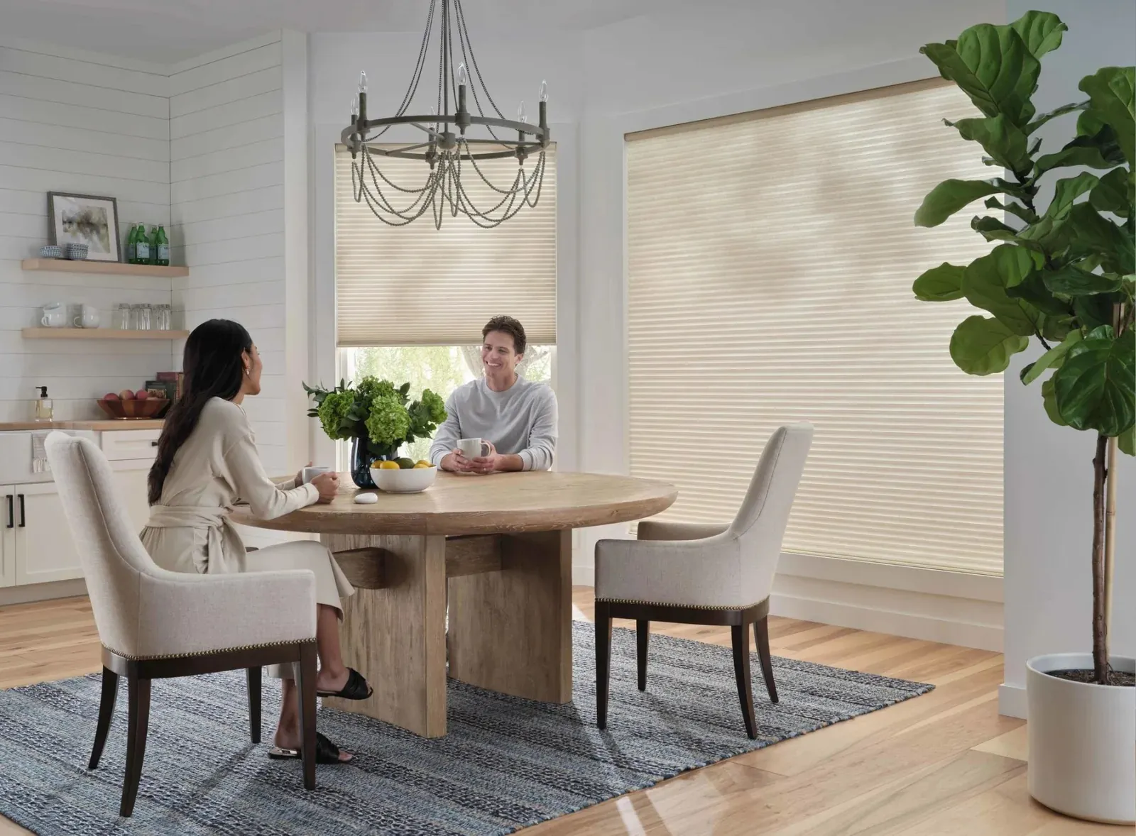 Two people meeting at a dining table in a bright room with light-filtering shades