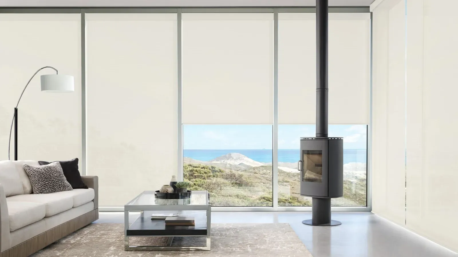 Designer screen shades on floor-to-ceiling windows with an ocean view